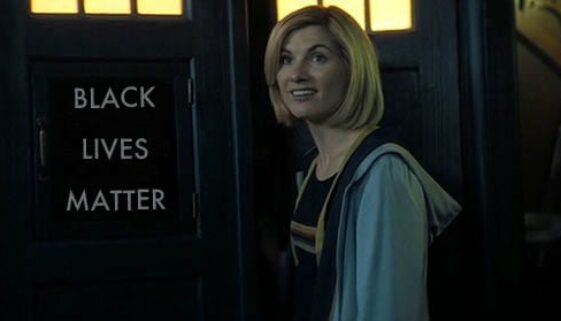 The 13th Doctor standing in front of the TARDIS, whose sign reads "Black Lives Matter"